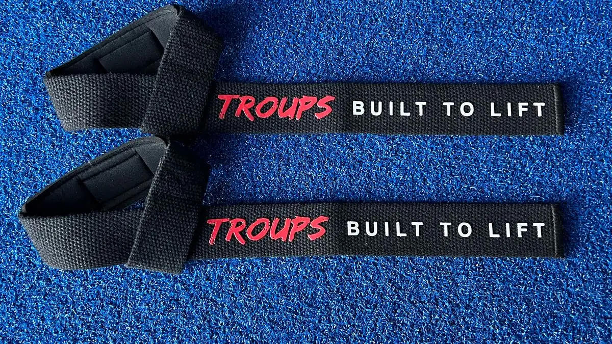 Par de straps Troups de algodón negro con el logo en rojo, sobre el suelo del gimnasio